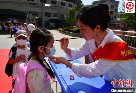 图为福州市高湖小学老师为一年级新生“点朱砂”启智。 张斌 摄